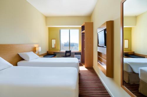 ドバイにあるIbis Deira Creekside Dubaiのベッド2台とテレビがあるホテルの部屋