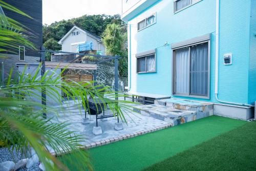 a backyard with green grass and a blue building at MF bloom in Minamiboso