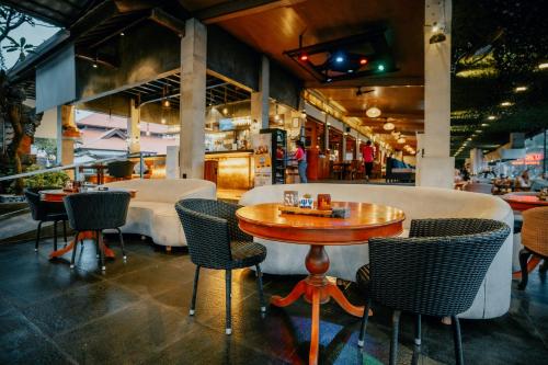 a restaurant with chairs and a wooden table and a table at Grand Istana Rama Hotel in Kuta