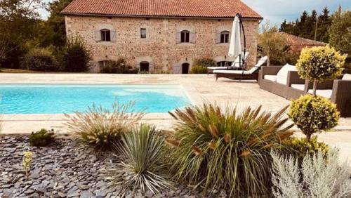 a house with a swimming pool in front of a building at TENDANCE CAMPAGNE Chambre d'hôtes in Marillac