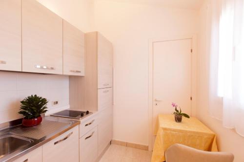 a small kitchen with white cabinets and a table at Fattoria Maremmana in Marina di Grosseto