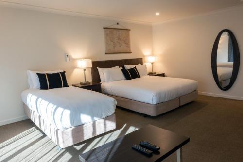 a hotel room with two beds and a mirror at Hanmer Springs Gateway Lodge in Hanmer Springs