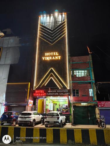een hotel waar 's nachts auto's voor geparkeerd staan bij Hotel Vikrant in Deoghar