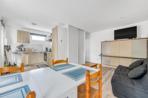 a kitchen and living room with a table and a couch at Studio Abygaelle in Lège-Cap-Ferret