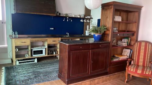 une cuisine avec un comptoir et un mur bleu dans l'établissement La Maison du Voyageur 1546 - studio, à Passavant