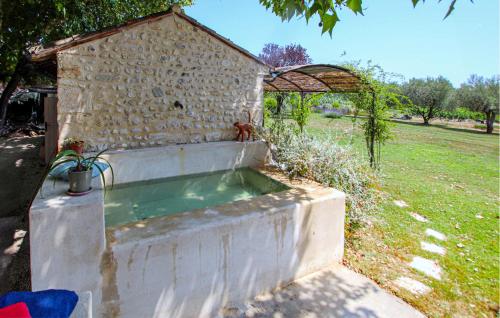 Un edificio de piedra con una bañera en un patio. en La Barralière, en Tulette