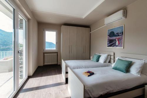 a hotel room with two beds and a balcony at Como Lake Amazing View - byMyHomeinComo in Moltrasio