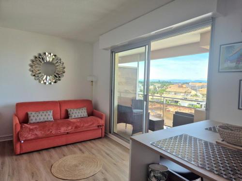 a living room with a red couch and a large window at Studio Marina & Soleil - Port de Canet in Canet-en-Roussillon
