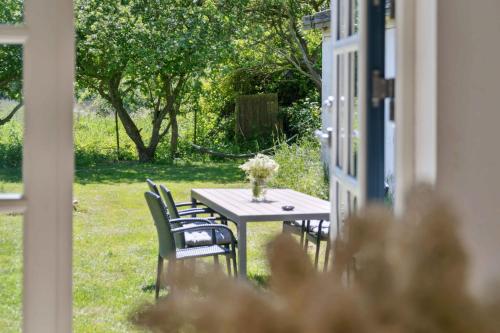 a table with chairs and a vase of flowers on it at Golf Holiday In Thatched House Near Langeland in Humble