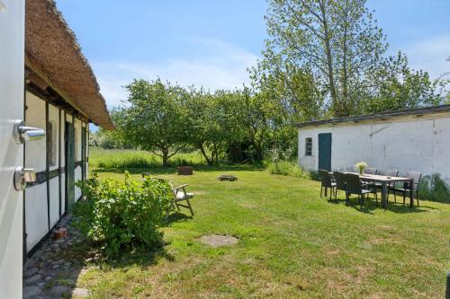 a table and chairs in a yard next to a building at Golf Holiday In Thatched House Near Langeland in Humble