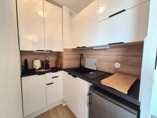 a kitchen with white cabinets and a wooden counter top at Studio Marina & Soleil - Port de Canet in Canet-en-Roussillon