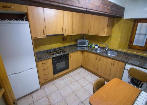 a small kitchen with wooden cabinets and a white refrigerator at Apartmento A in Benasque