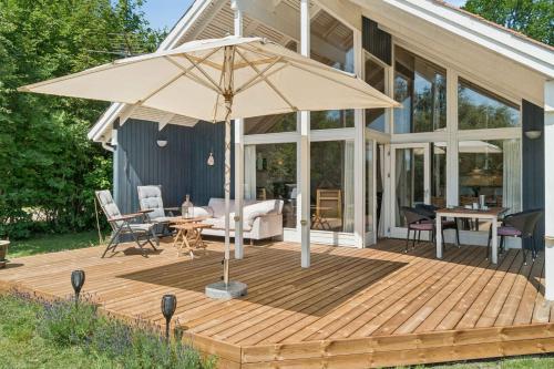 a wooden deck with an umbrella in front of a house at Cosy Cottage With Open View Of The Meadow in Store Fuglede