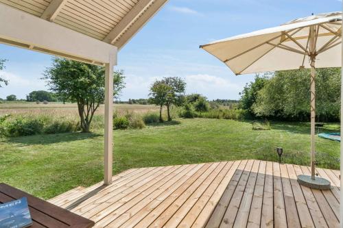 a wooden deck with an umbrella and a field at Cosy Cottage With Open View Of The Meadow in Store Fuglede