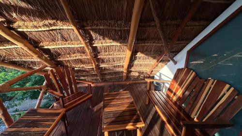 two chairs sitting on the porch of a straw roof at Hotel Aldea Maya in Valladolid