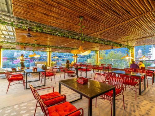 a restaurant with tables and chairs and people sitting at them at The Hosteller Rishikesh, Ganges in Rishīkesh
