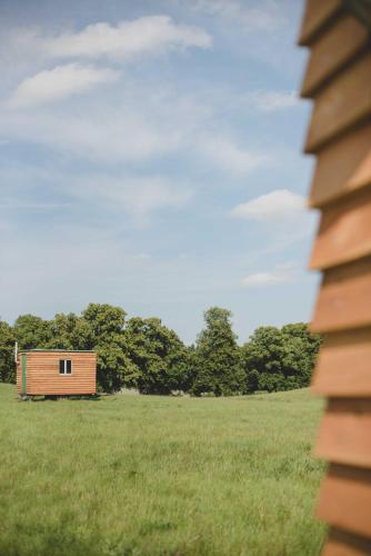 a small wooden building in a field with trees at Farm Cabin im Grünen in Wardow