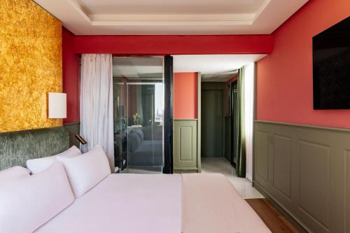 a bedroom with a white bed and a red wall at Hotel Colón Gran Meliá - The Leading Hotels of the World in Seville