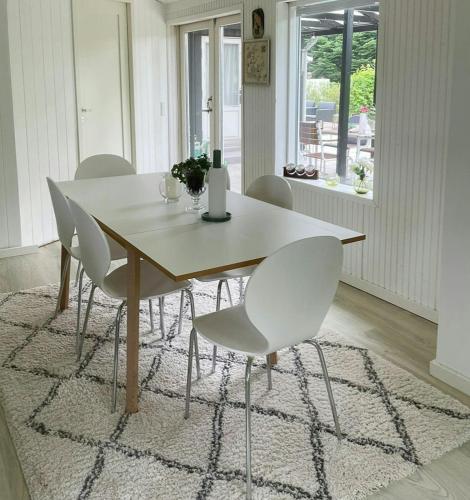 a dining room table with white chairs in a room at Retro Cottage With Fjord View in Storvorde