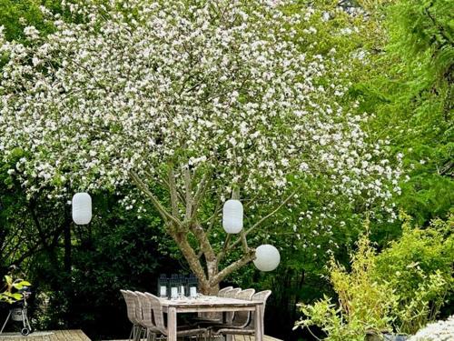 a table and chairs under a tree with white flowers at Holiday Home With Wild Garden Near Tisvilde Beach in Tisvilde
