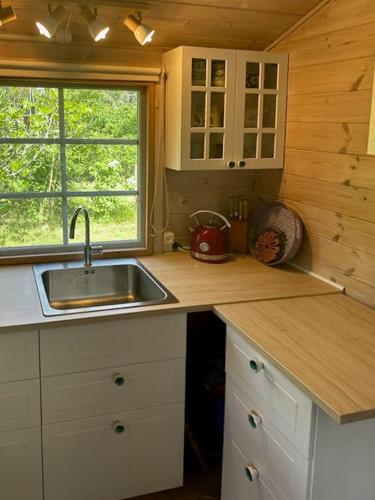 a kitchen with a sink and a window in a cabin at Blue Cottage On Idyllic Askø in Maribo