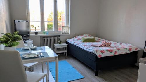 a small bedroom with a bed and a table and a tv at Kasarminkadun Basic Cozy 19,5 m2 in Vaasa