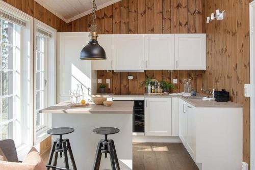a kitchen with white cabinets and bar stools at Mountain Cabin With Panoramic Views In Sjusjøen in Sjusjøen