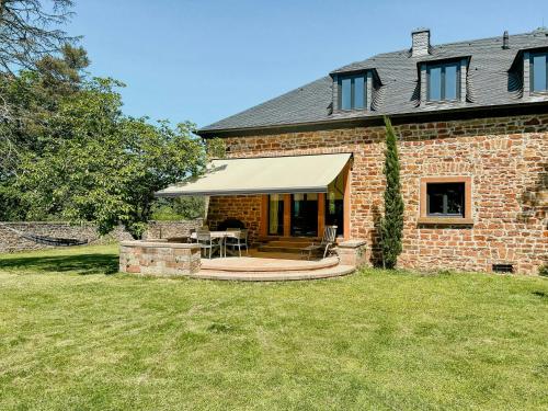 a brick house with awning and a patio at Renovated Farmhouse Half In The Trierer Heide in Trier