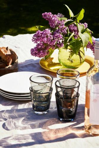 a table with plates and a vase with purple flowers at Personally Furnished Holiday Home Near The Beach in Vejby