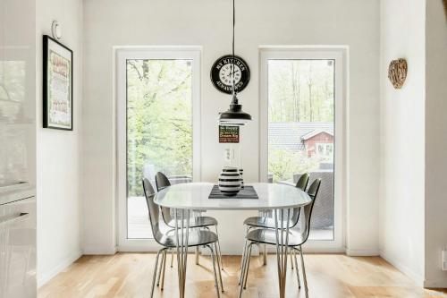 a dining room with a table and chairs and a clock at Modern Stone House With Hot Tub In Åsljunga Forest in Orkelljunga