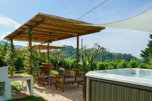a patio with a hot tub and a wooden umbrella at Tuscan Villa With Sea View And Jacuzzi in Fosdinovo