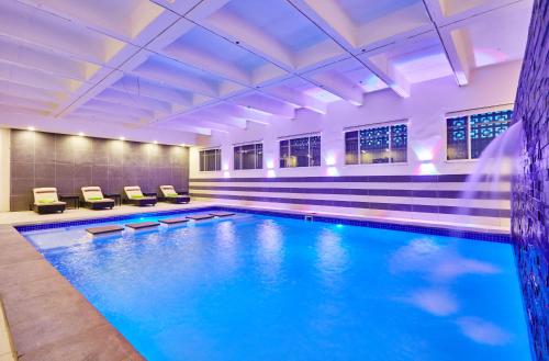 a large swimming pool with blue water in a building at Palm Continental Hotel in Johannesburg