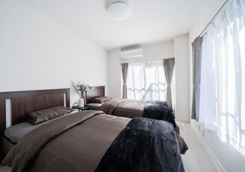 Un dormitorio con dos camas y una ventana. en Kasai Light Luxury Hotel 301, en Tokio