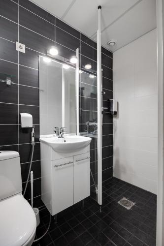 a bathroom with a white sink and a toilet at Hotel Käenpesä in Ylivieska