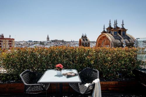 a table and chairs on a balcony with a view of a city at Hotel Colón Gran Meliá - The Leading Hotels of the World in Seville