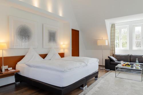 a bedroom with a large white bed and a couch at Neumühle Resort & Spa in Hammelburg