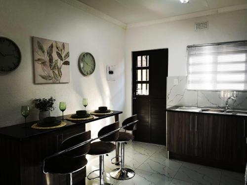 a kitchen with bar stools and a clock on the wall at Carissa Street Self-catering Units in Burgersfort