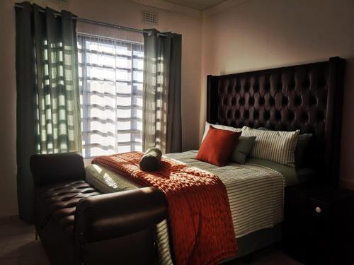 a bedroom with a bed and a chair and a window at Carissa Street Self-catering Units in Burgersfort
