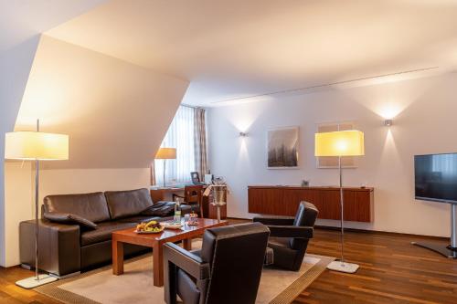 a living room with a couch and a tv at Neumühle Resort & Spa in Hammelburg