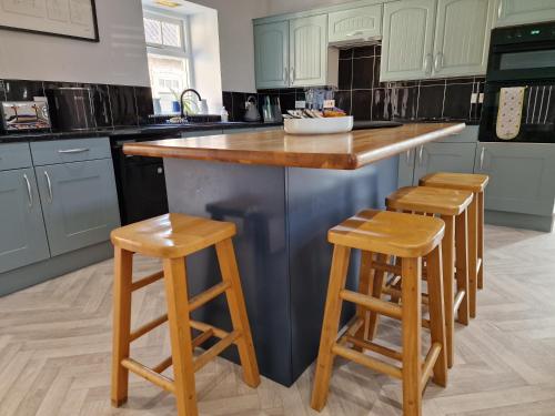 a kitchen with a island with two wooden stools at Southbarn - Spectacular Country Home in Winestead