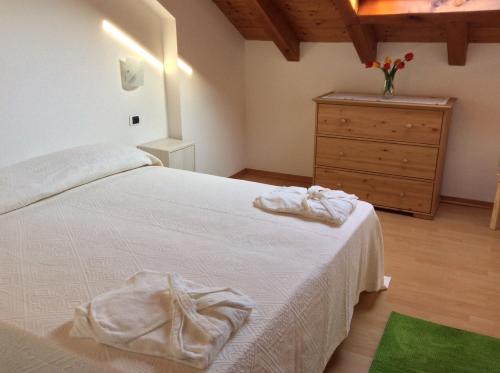 a bedroom with a white bed and a dresser at Appartamento A Due Passi in Farra dʼAlpago