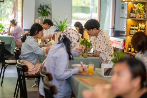 a group of people sitting at tables in a restaurant at Jana Hotel & Apartment - Firework & Aquatopia Water Park in Phu Quoc