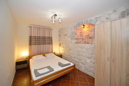 a bedroom with a bed and a brick wall at Kuzman Apartments in Kotor