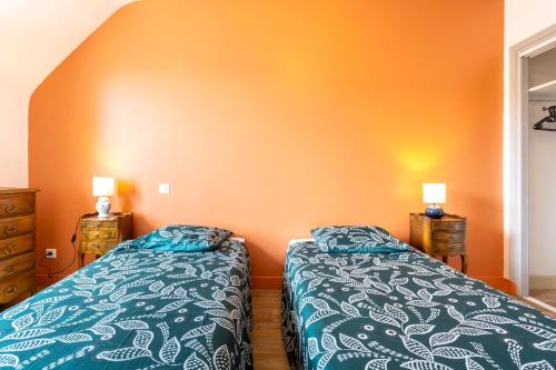 two beds in a bedroom with an orange wall at Villa Nicole face mer in Trégunc