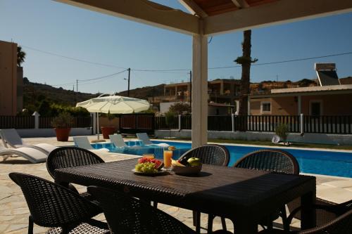 a table with a bowl of fruit and an umbrella on a patio at Villa Aelia Kefalos-Private & Spacious with Pool in Kámpos