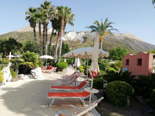 a group of chairs and an umbrella and palm trees at casa giardino in Vulcano