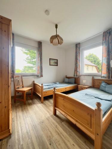 a bedroom with two beds and a chair and two windows at Große Ferienwohnung mit Weitblick in Wesenberg