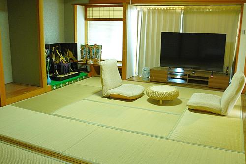 a living room with two chairs and a flat screen tv at Kototoki-Ren-401 Deluxe Family Suite room in Hiroshima