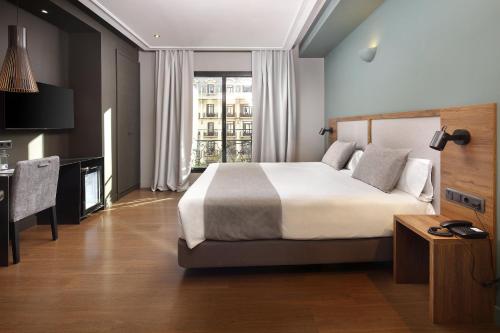 a hotel room with a bed and a desk and a window at Wilson Boutique Hotel in Barcelona