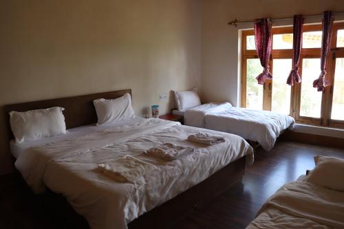 a bedroom with two beds and a window at Nilza Guest House in Leh